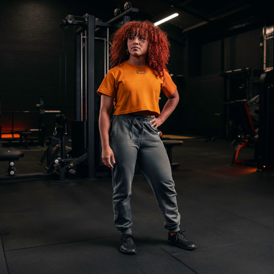 SBD Crop Top - Forge Limited Edition – oranje crop top gedragen met een grijze broek
