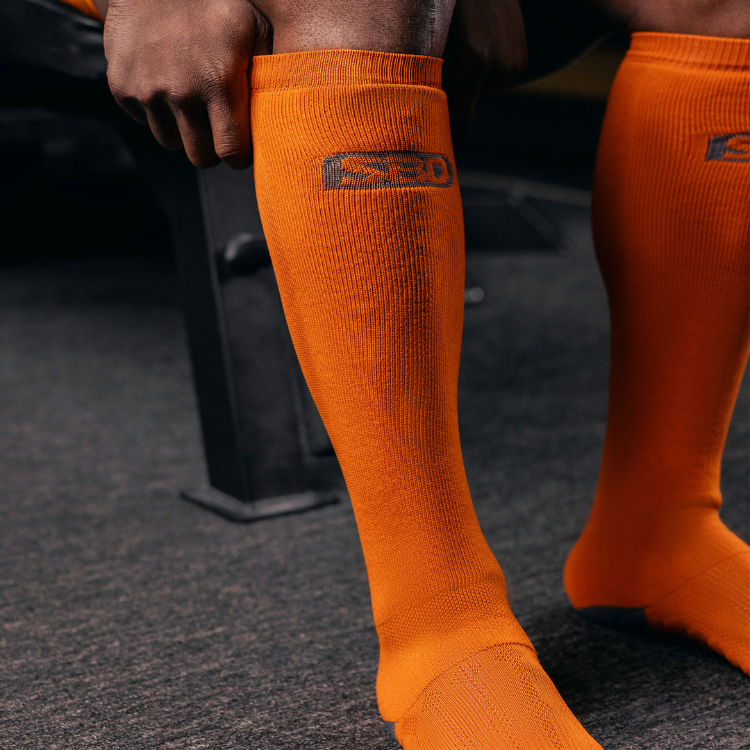 SBD Deadlift Sokken - Forge Orange Limited Edition – oranje deadliftsokken met grijze tenen worden aangetrokken