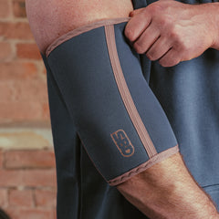SBD Elbow Sleeves - Serenity Limited Edition – blauwgrijze sleeve met roze afwerking gedragen door een man