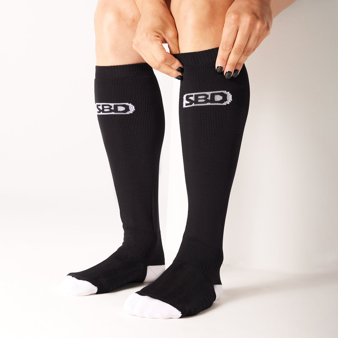 SBD Deadlift socks MOMENTUM Limited Edition – detail van het aantrekken van een lange zwarte sok