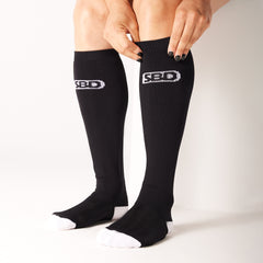 SBD Deadlift socks MOMENTUM Limited Edition – detail van het aantrekken van een lange zwarte sok