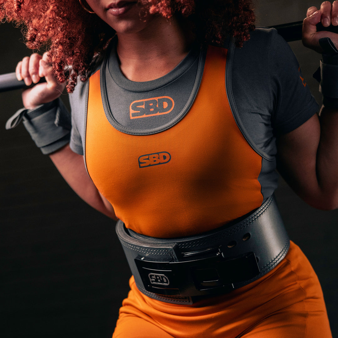 SBD Powerlifting Singlet Forge Orange Limited Edition – detail van de borst en pasvorm van het oranje damesmodel