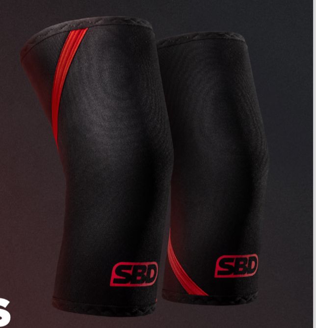 SBD Knee Sleeves 7mm – paar zwart-rode knee sleeves tegen een donkere achtergrond