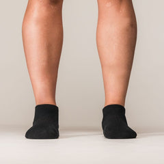 Model draagt zwarte SBD Trainer Socks Classic met wit SBD-logo – studiofoto