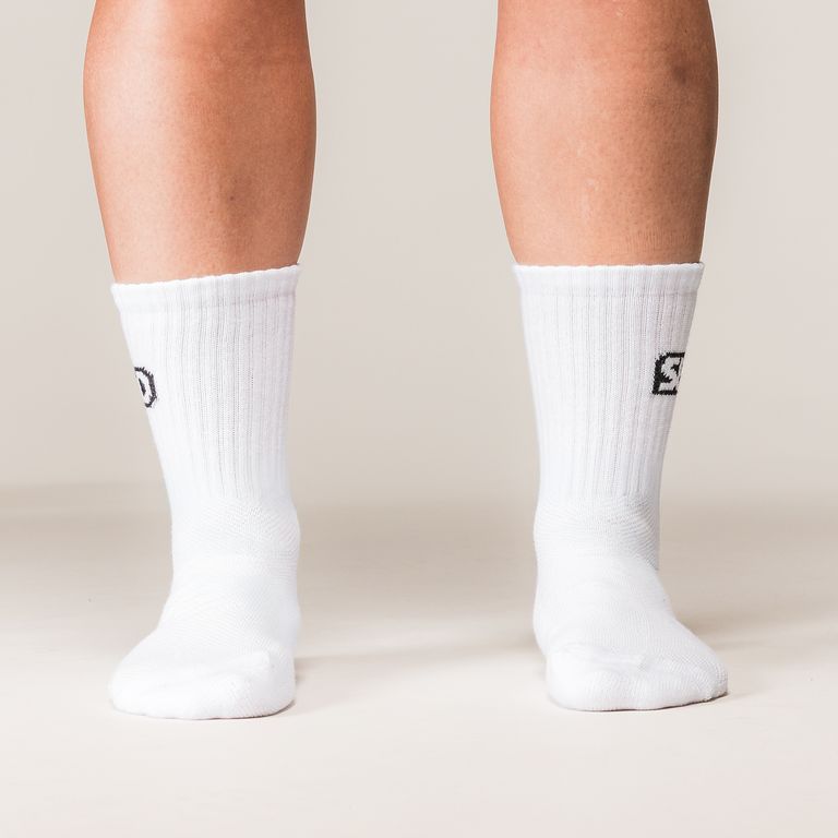 Model draagt witte SBD Crew Socks Classic met zwart SBD-logo – studiofoto