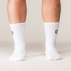 Model draagt witte SBD Crew Socks Classic met zwart SBD-logo – studiofoto