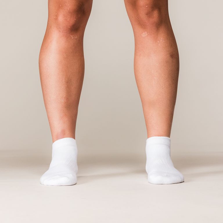 Model draagt witte SBD Trainer Socks Classic met zwart SBD-logo – studiofoto