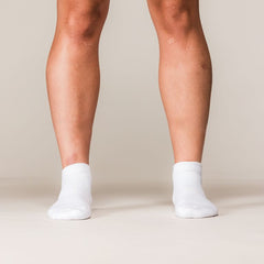 Model draagt witte SBD Trainer Socks Classic met zwart SBD-logo – studiofoto