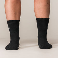 Model draagt zwarte SBD Crew Socks Classic met grijs SBD-logo – studiofoto