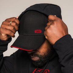 Mannelijk model draagt de SBD Baseball Cap Classic in zwart – studiofoto 2